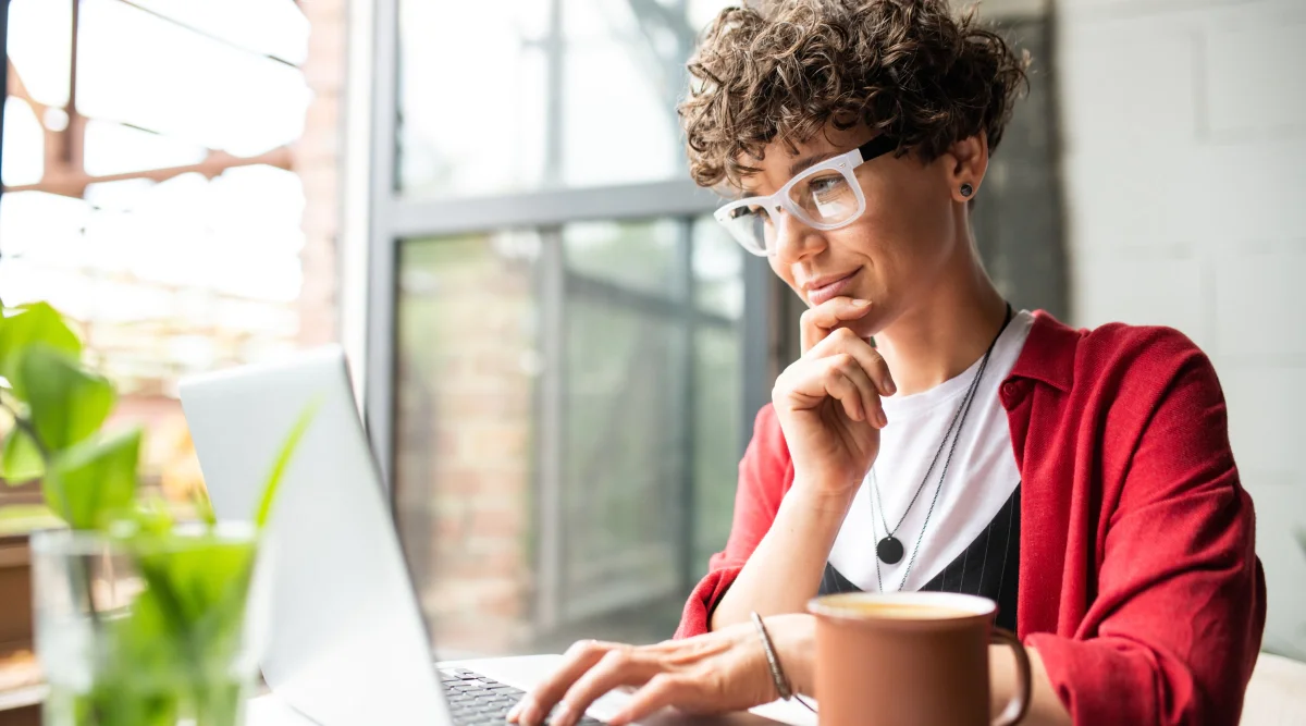 A woman browsers her computer in a modern, well-lit apartment