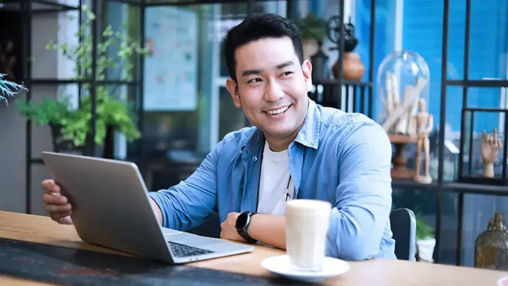 A cafe owner works on his laptop to form an out-of-state LLC. Annual fees are something to be aware of if you're considering forming an LLC that you don't reside in.